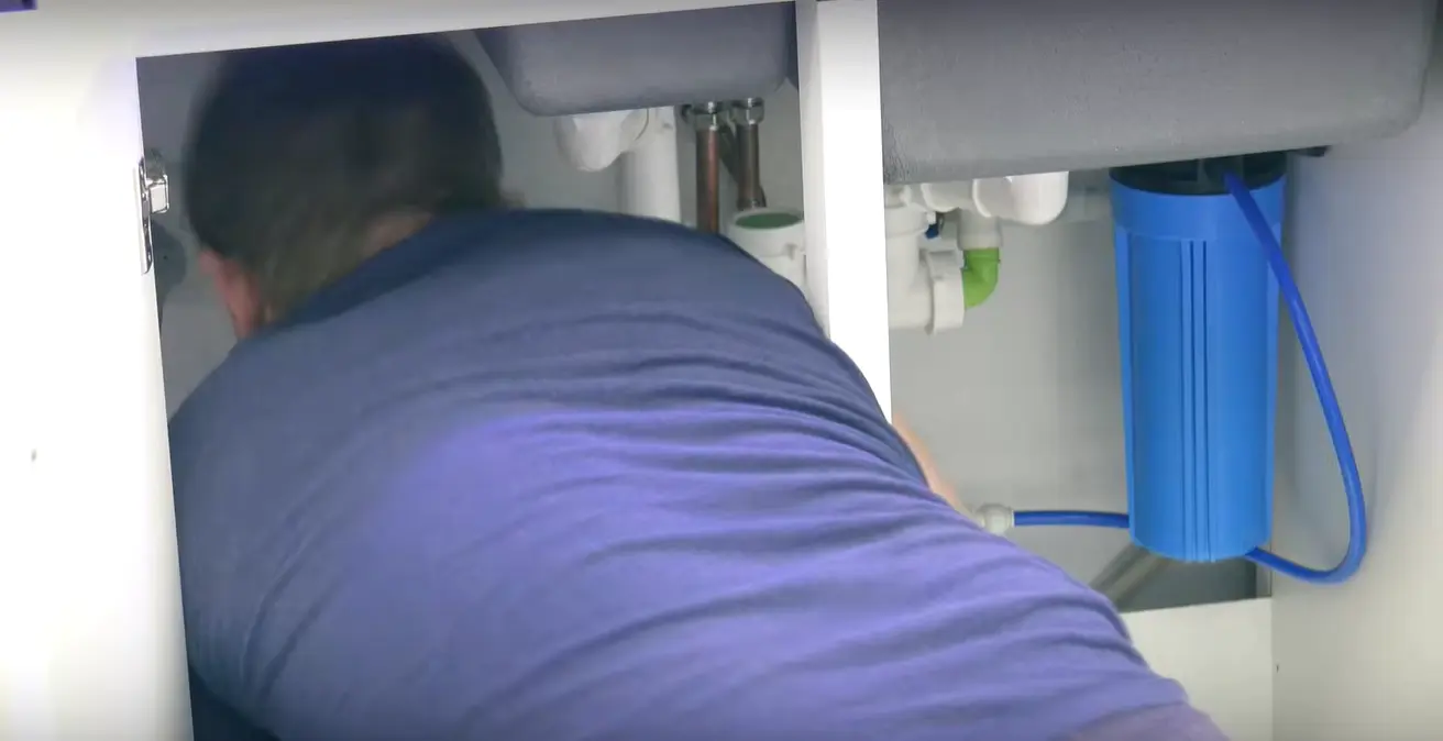 Caucasian woman in PPE holding a plumber's wrench indoors, focused on maintenance.