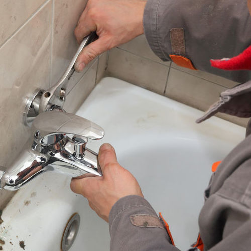 A Plumber Repairs a Bathroom Faucet.